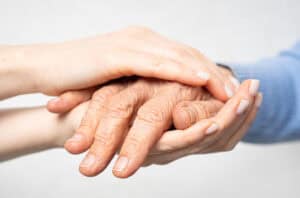 Younger person holds hand of older family member.