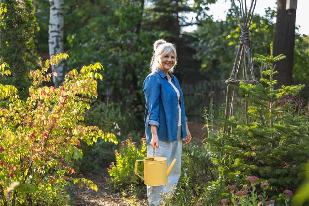 older adult holds watering can outdoors - cremation services